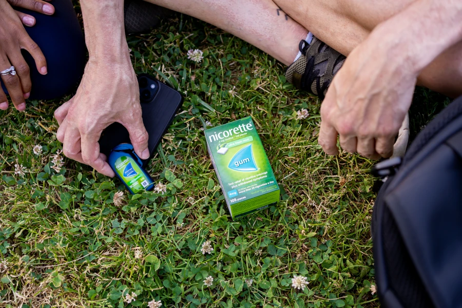  A man resting a pack of NICORETTE Lozenges and NICORETTE Gum on the ground